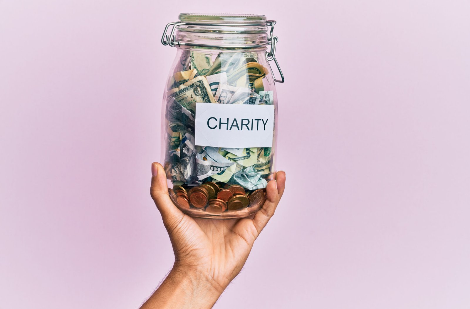 hand hispanic man holding charity jar with dollars isolated pink background scaled